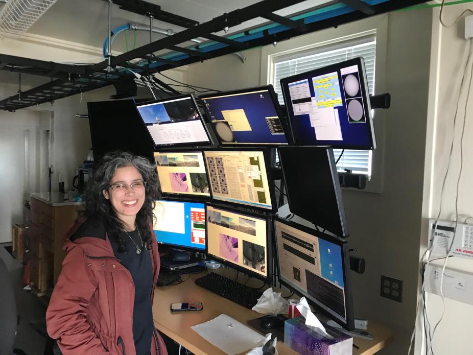 Lisa standing in front of the monitoring displays at the MLSO observatory