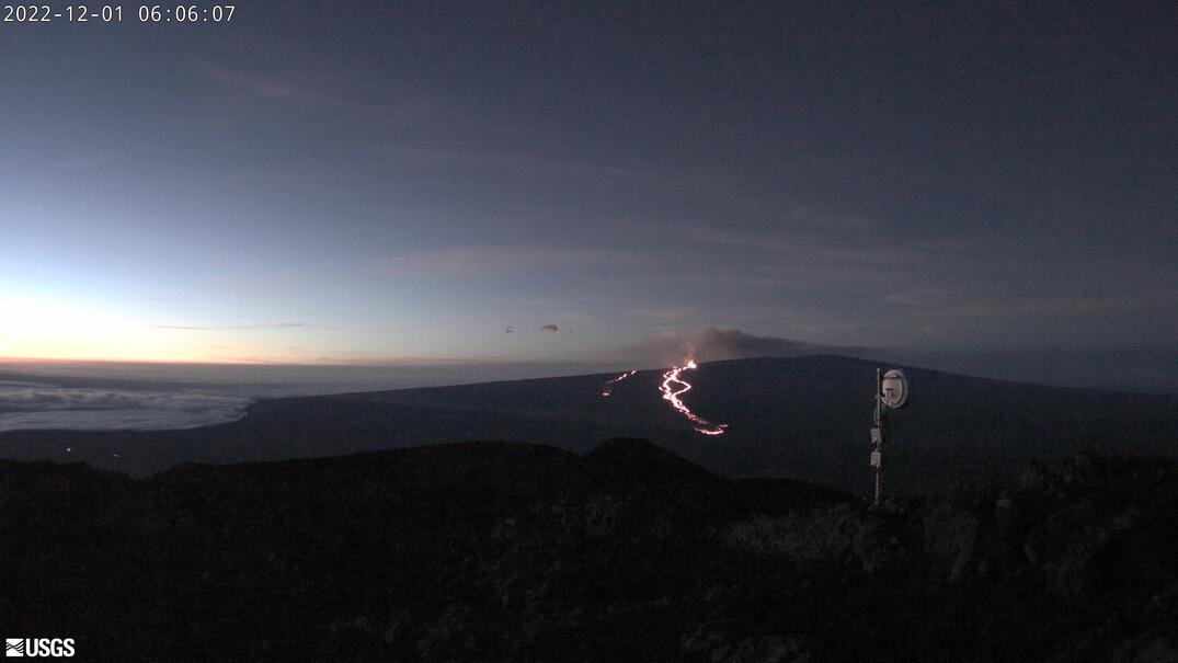 USGS webcam image from Dec 1 at 06:06 AM Hawaii time from Mauna Kea shows the lava flows continuing in the northeast rift zone on Mauna Loa flowing downslope toward the Saddle Road.
