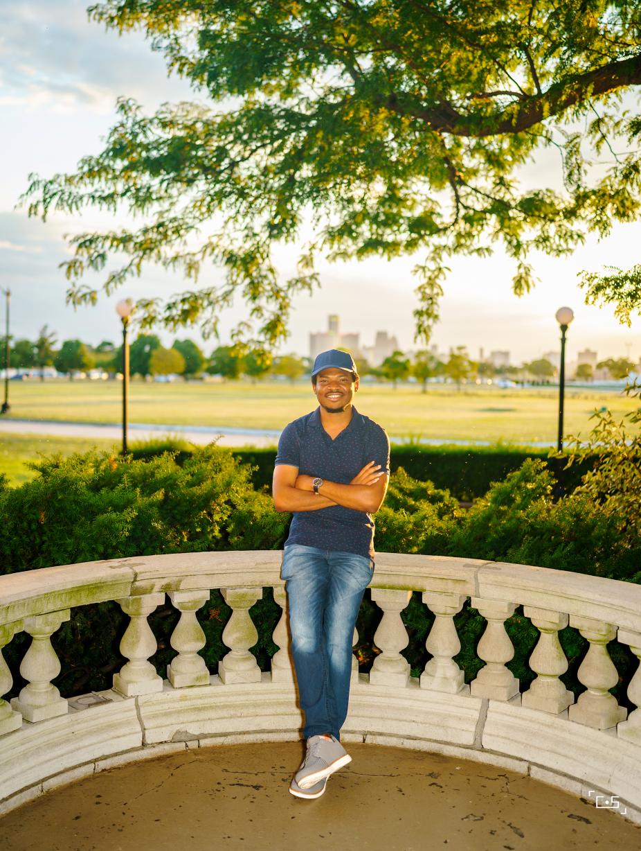 Outdoors, smiling and standing against a patio railing