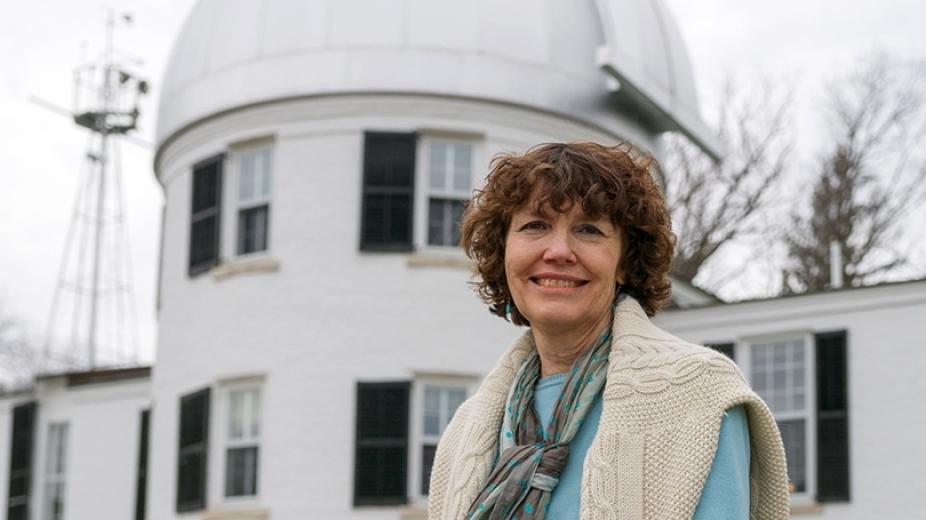Mary Hudson smiling in front of a observatory building at Dartmouth College