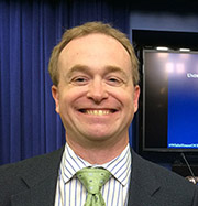 Mike smiling with gray suit and bright green tie