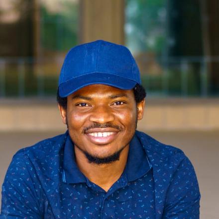 Amadi wearing a bright blue cap and smiling