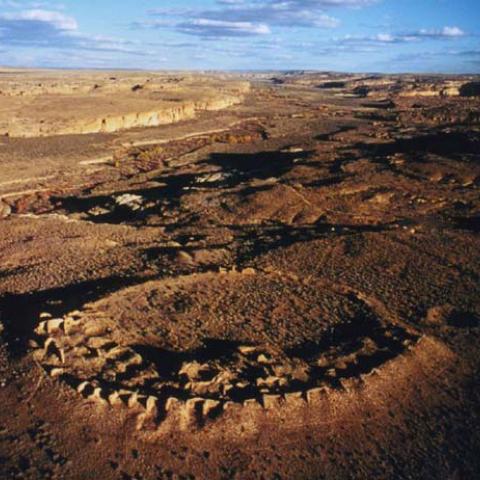 Aerial view of Chaco Canyon at sunset, looking approximately East. The circular structure in the foreground is the unexcavated ruin of Peñasco Blanco, the westernmost large dwelling in Chaco Canyon